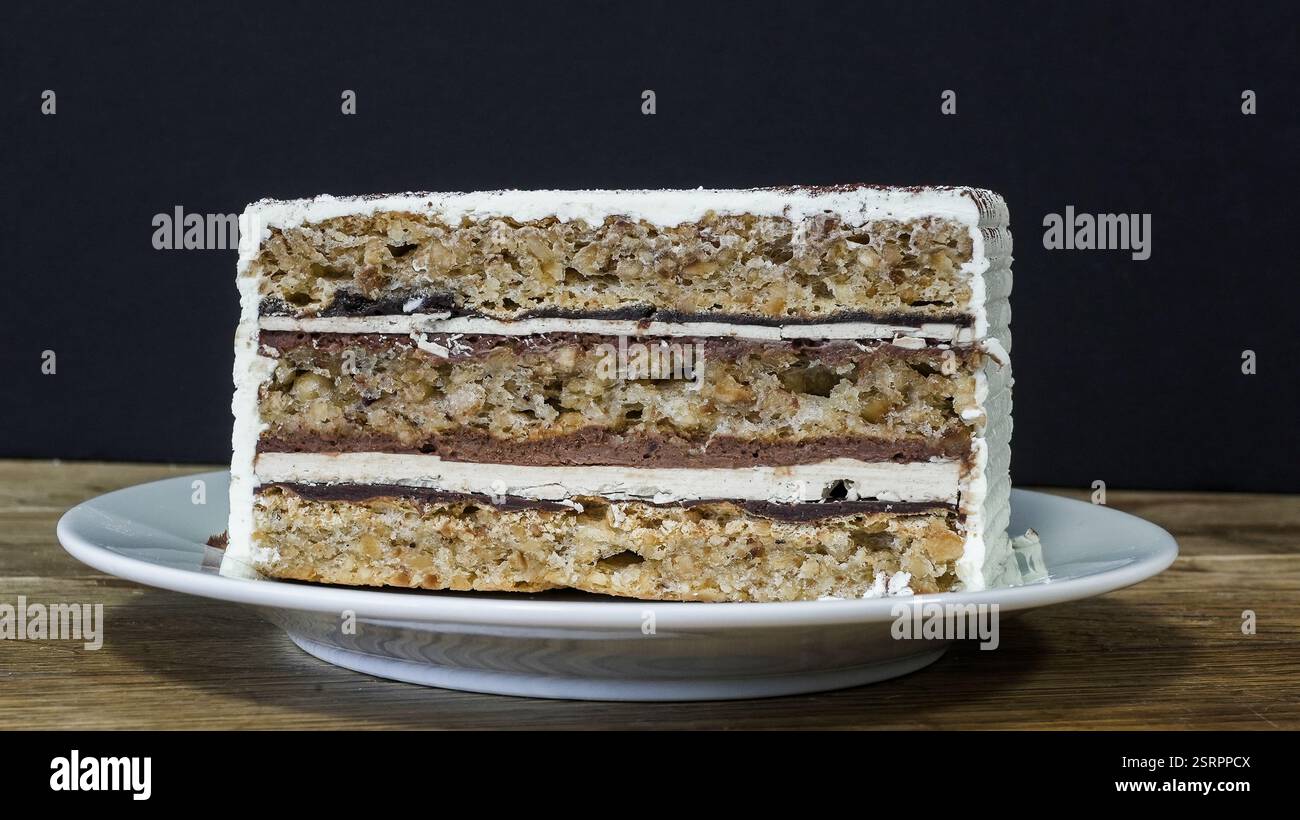 Un gâteau superposé magnifiquement conçu avec de la crème et des noix se trouve sur une assiette, soulignant ses textures et saveurs attrayantes. Banque D'Images
