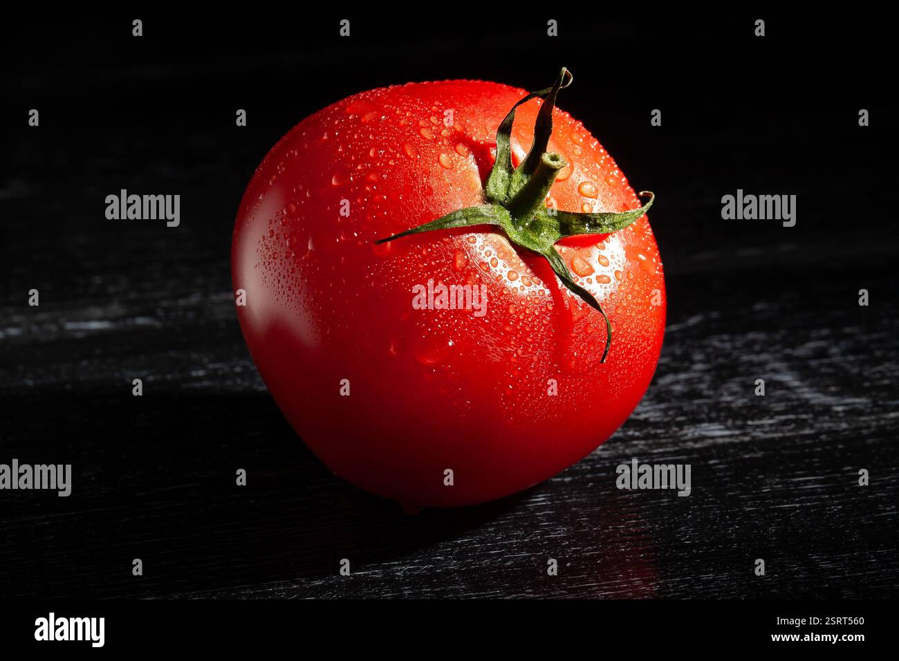 tomate sur fond de bois noir humide Banque D'Images
