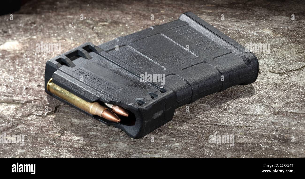 Chargeur en plastique pouvant contenir dix cartouches 5,56 qui contient des munitions à l'intérieur et repose sur un gros rocher. Banque D'Images