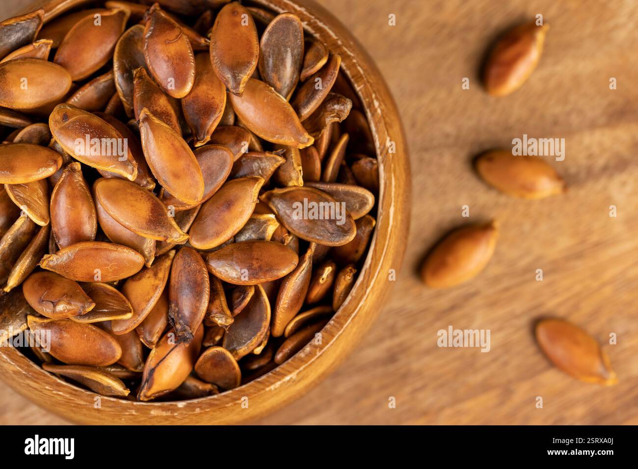 graines de citrouille dans un bol en bois gros plan, graines de citrouille trop cuites ou brûlées sur la table Banque D'Images