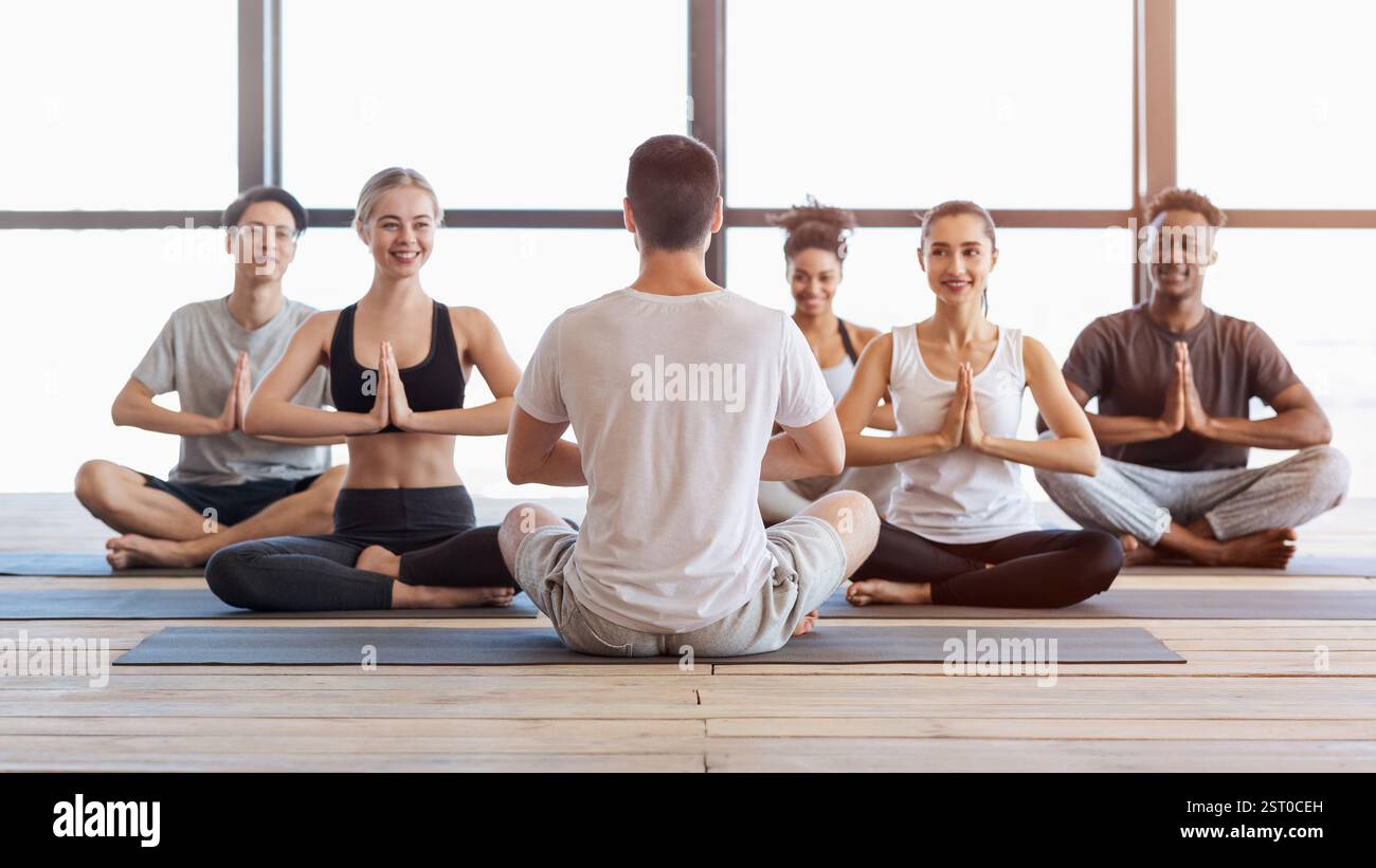 Groupe international de jeunes participant à des cours de yoga dans un studio moderne Banque D'Images
