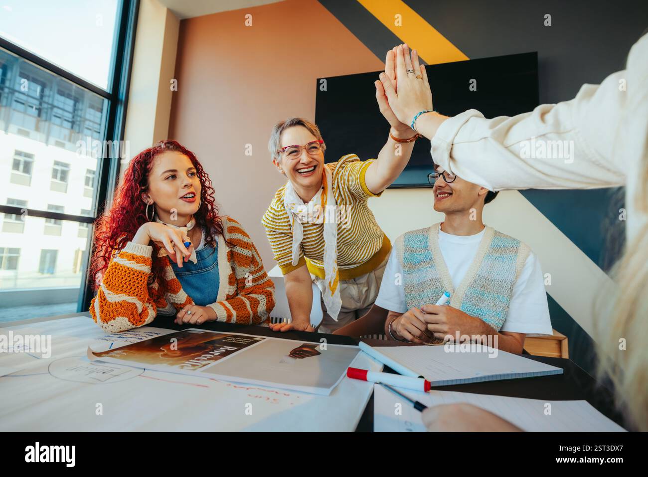 Un enseignant joyeux élève les élèves dans un milieu d'école secondaire, favorisant un environnement d'apprentissage motivant et collaboratif. Banque D'Images