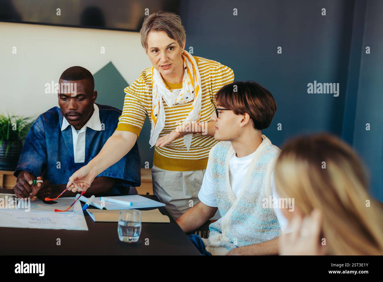 Éducateur guidant les jeunes élèves à travers une discussion engageante, cultivant la participation active et le travail d’équipe dans un cadre éducatif diversifié. Banque D'Images
