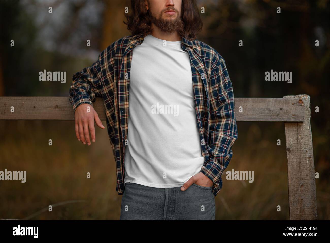 Maquette de T-shirt blanc sur un gars rustique dans une chemise à carreaux, sur fond d'arbres, de nature. Modèle de T-shirt propre à la mode sur un homme avec un Banque D'Images