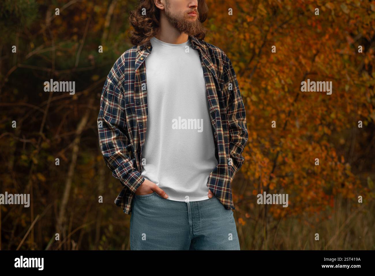 Maquette de T-shirt blanc sur un gars dans une chemise en flanelle à carreaux, sur un fond de nature. Modèle de T-shirt propre à la mode sur un homme avec une barbe, long ha Banque D'Images