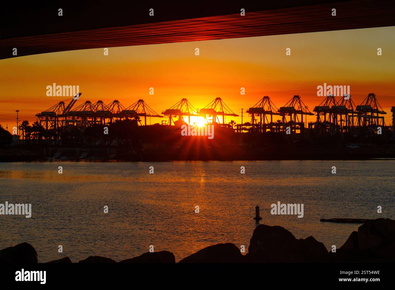Long Beach, Californie - 11 janvier 2025 : coucher de soleil sur le port de long Beach, mettant en valeur la silhouette de grues reflétant dans l'eau, mettant l'accent sur l'industrie Banque D'Images