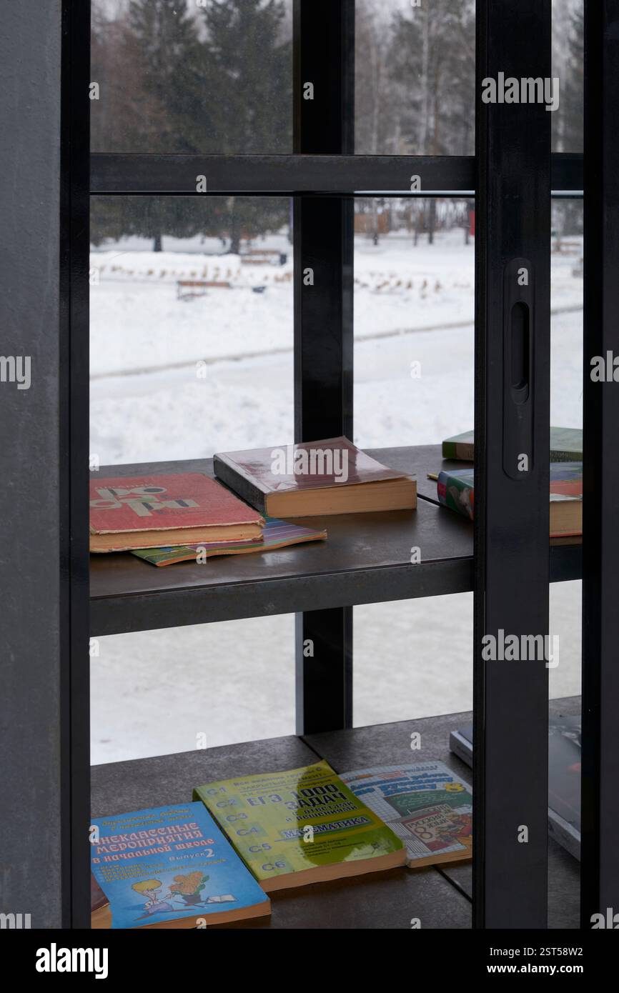 Ekaterinbourg, Russie - 14 février 2025 : gros plan de livres sur des étagères métalliques à l'intérieur d'un kiosque public d'échange de livres dans le parc enneigé. Des livres sont disponibles pour Banque D'Images