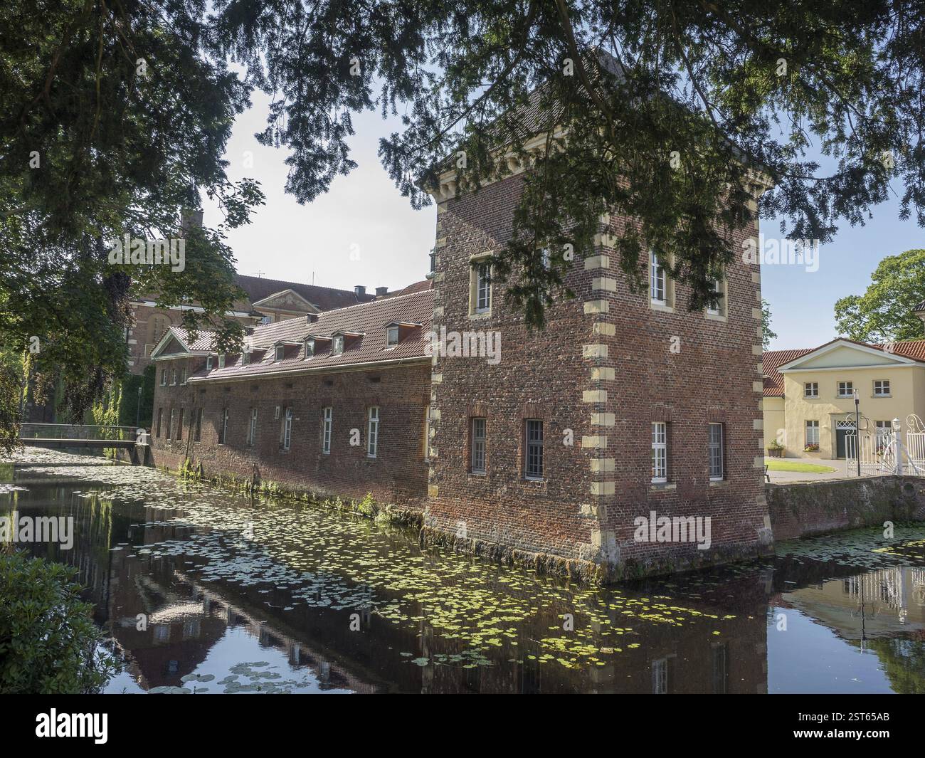 Une tour de briques et un bâtiment par un fossé recouvert de nénuphars, velen, westphalie, allemagne Banque D'Images