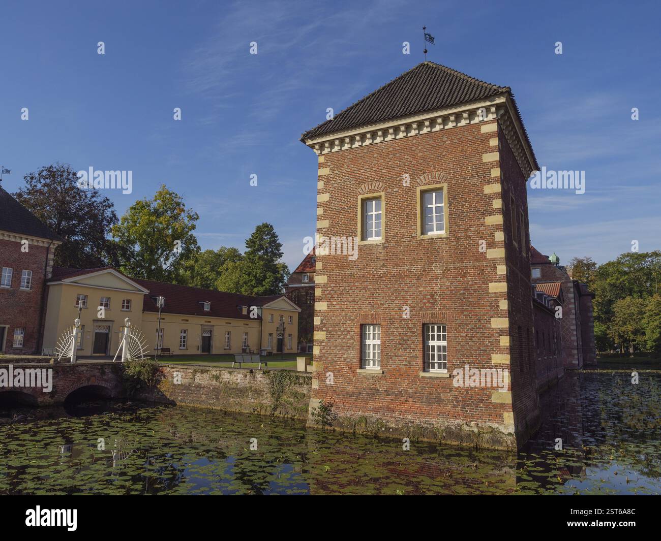 Bâtiment rectangulaire en briques avec fenêtres, entouré d'un étang plein de nénuphars sous un ciel bleu, velen, westphalie, allemagne Banque D'Images