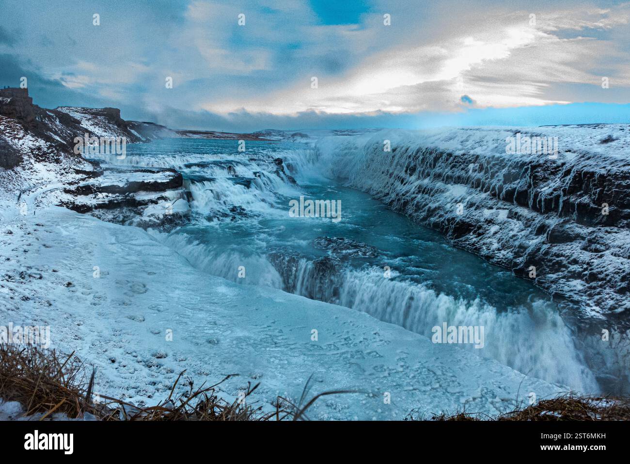 Cascade Gullfoss en Islande. Une puissante cascade glaciaire affichant des tons bleus glacés contre des falaises enneigées de chaque côté. Banque D'Images