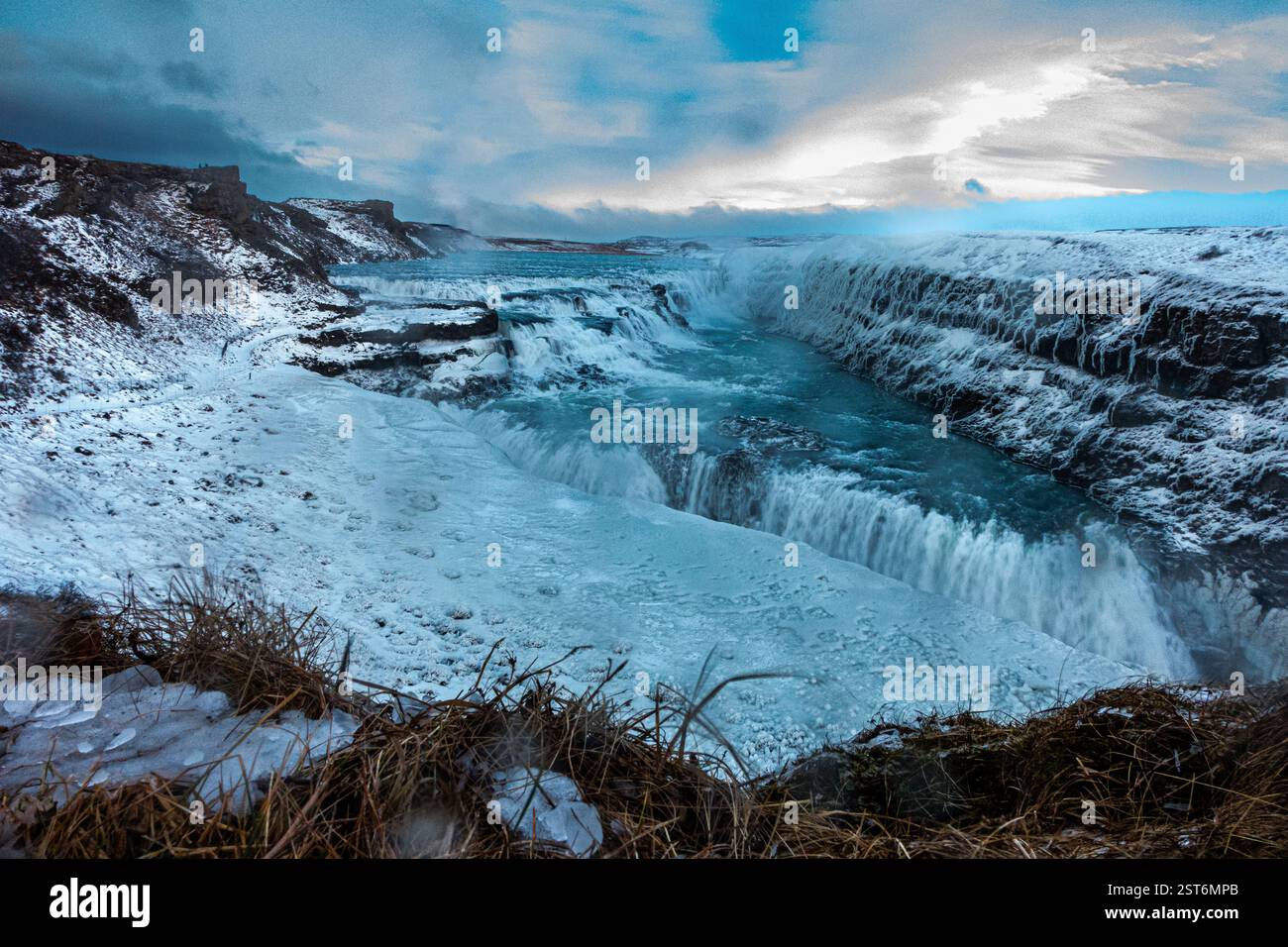 Cascade Gullfoss en Islande. Une puissante cascade glaciaire affichant des tons bleus glacés contre des falaises enneigées de chaque côté. Banque D'Images