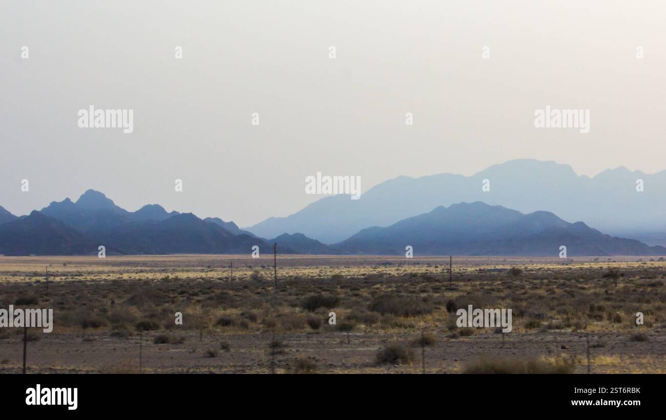 Spectaculaires montagnes bleues s'élevant au loin le long du bord du désert du Namib en Namibie. Banque D'Images