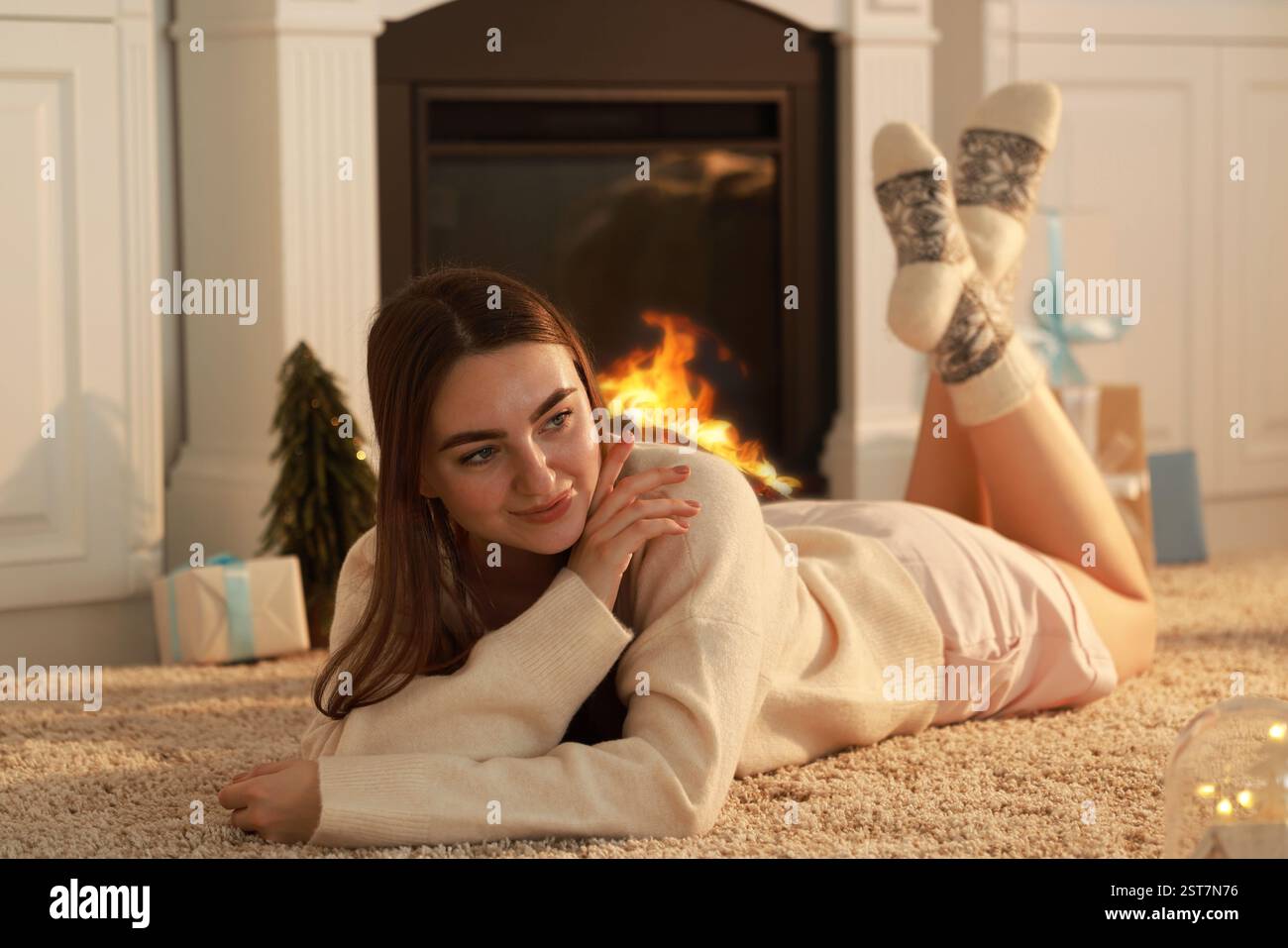 Femme dans des chaussettes chaudes reposant près de la cheminée à la maison Banque D'Images