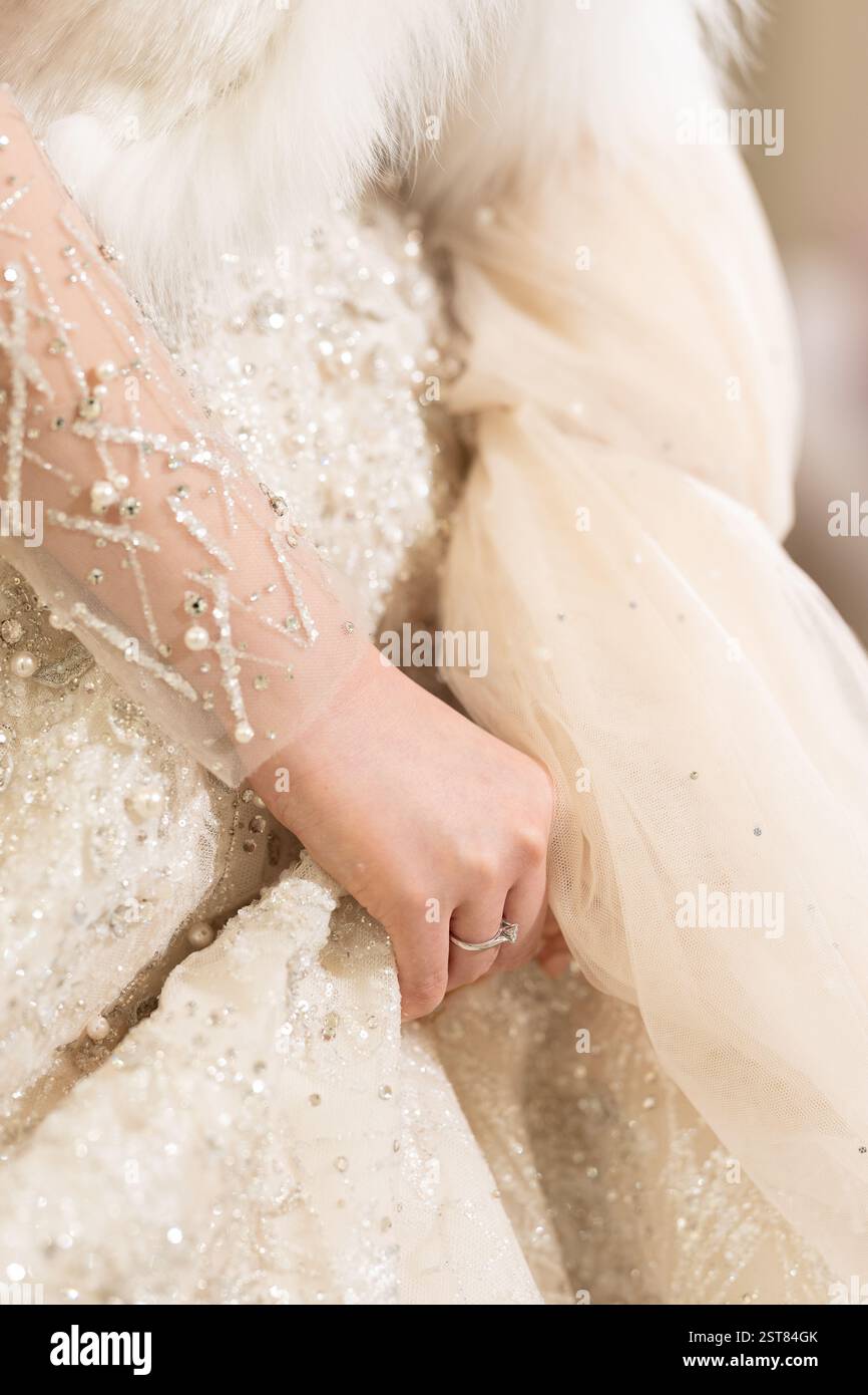 La femme porte une robe blanche avec un col en fourrure. Elle tient une bague dans sa main Banque D'Images