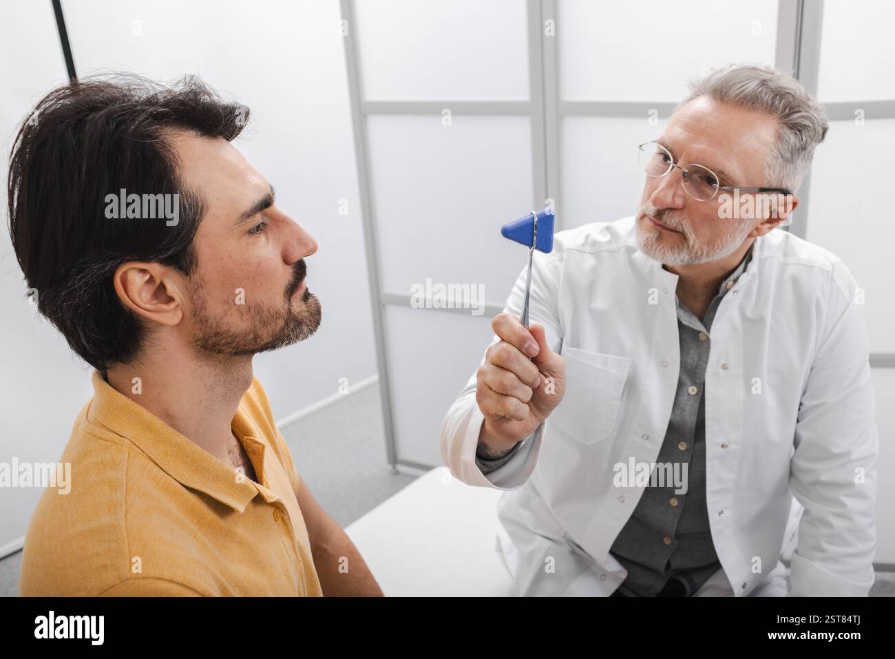 L'examen neurologique. Médecin neuropathiste contrôle le système nerveux et les réflexes du patient masculin à l'aide d'un marteau neurologique au cabinet médical Banque D'Images