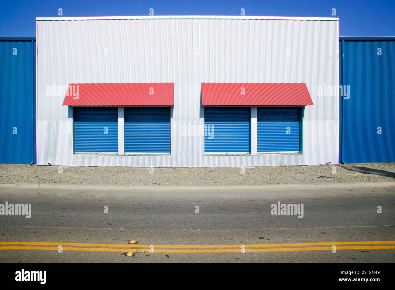 Entrepôt audacieusement conçu avec des détails minimalistes, des murs bleus profonds et un auvent rouge contrasté, mettant en valeur l'esthétique architecturale urbaine. Banque D'Images