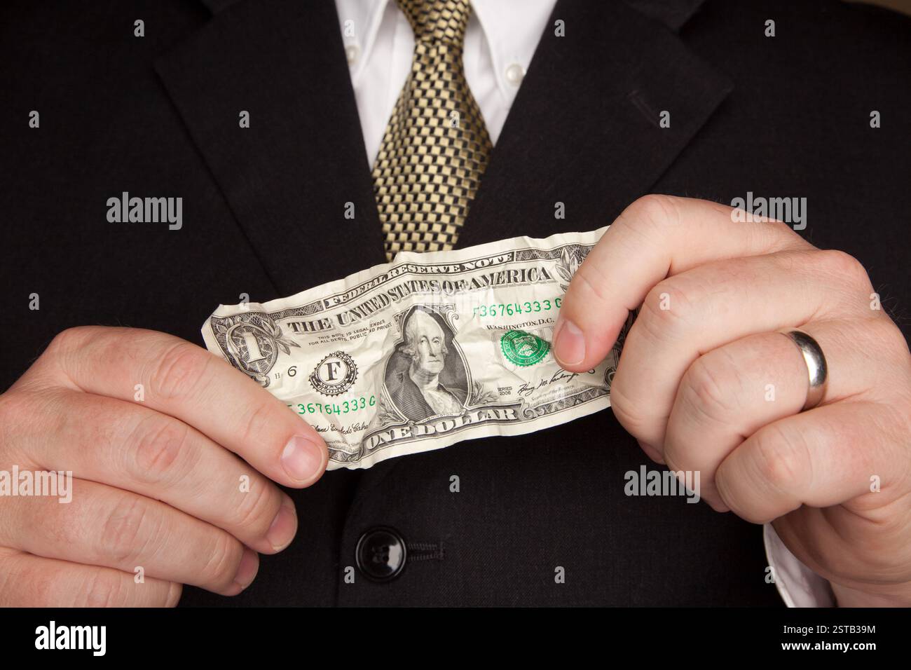 Homme d'affaires avec manteau et cravate tenant le billet de dollar des États-Unis ridé. Banque D'Images