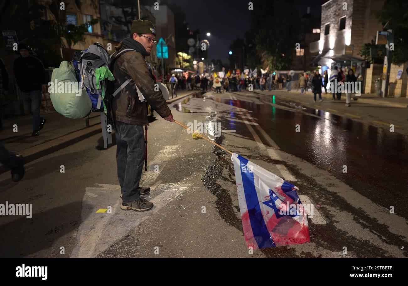 JÉRUSALEM - 17 FÉVRIER : un manifestant trempe un drapeau israélien dans de l'eau teinte en rouge symbolisant le sang versé dans la rue, lors d'une manifestation près de la résidence privée du premier ministre Netanyahou, marquant 500 jours de captivité pour les otages détenus par le Hamas à Gaza et exhortant les dirigeants israéliens à conclure l'accord de libération des otages avec le Hamas et à assurer le retour des prisonniers restants détenus à Gaza le 17 février 2025 à Jérusalem. Israël Banque D'Images