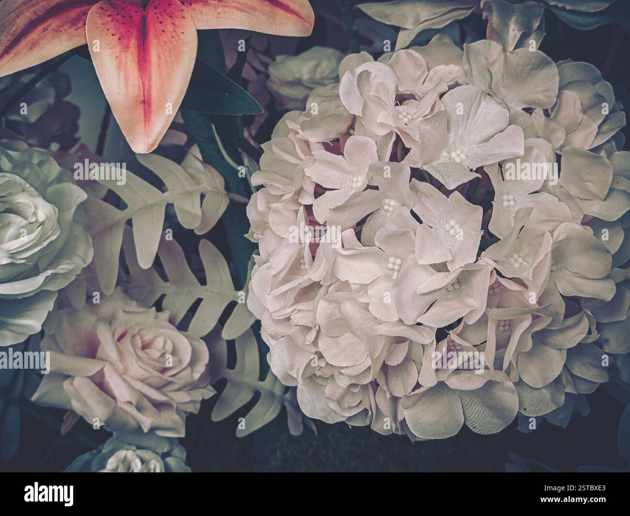 Vintage floral nature morte présente des roses roses roses et blanches douces avec un lis orange, créant une esthétique discrète, classique et vieillie. Banque D'Images