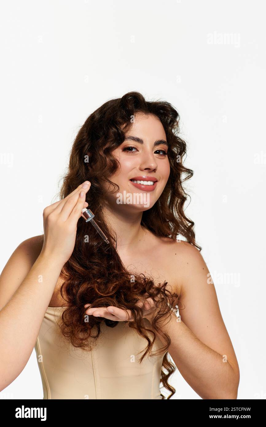 Femme élégante avec les cheveux bouclés améliore son look tout en souriant et en appliquant le produit capillaire à l'intérieur. Banque D'Images