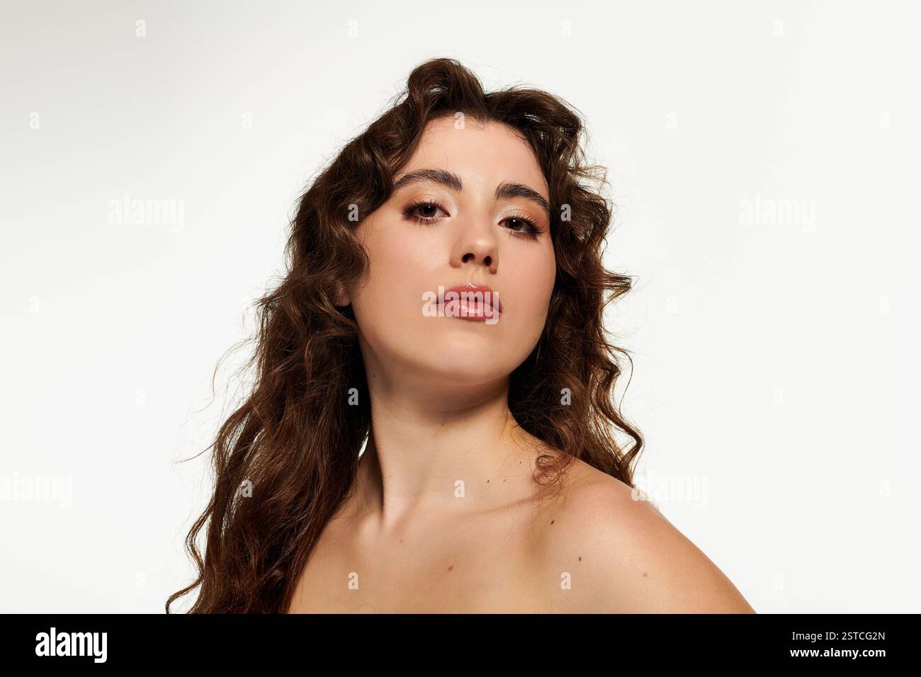 Une jeune femme élégante aux cheveux ondulés rayonne de confiance dans une pose saisissante. Banque D'Images