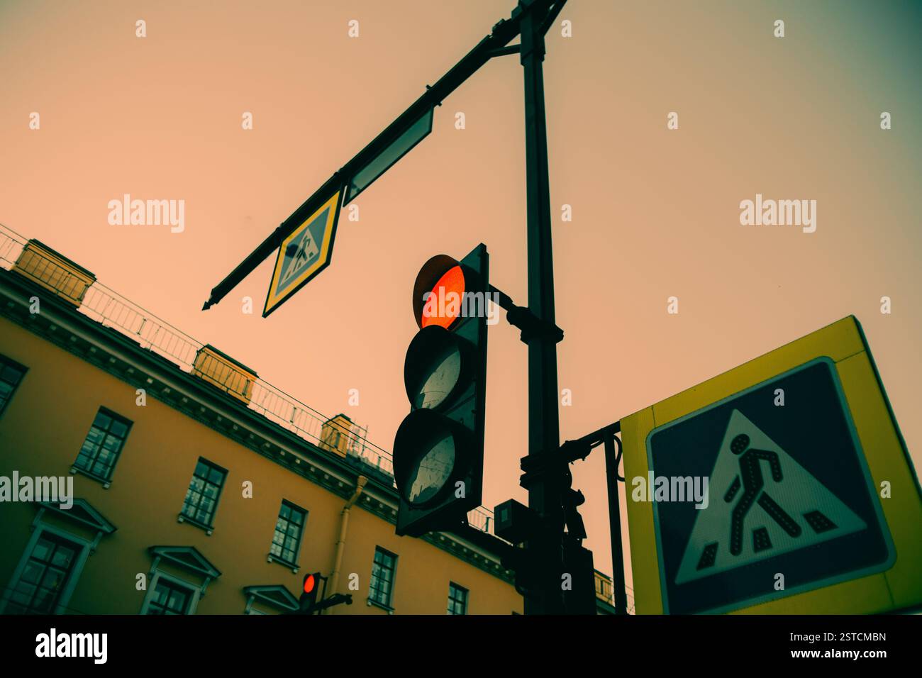 Un soir d'été, les panneaux de passage pour piétons et le feu rouge se détachent sur fond de l'horizon et des bâtiments. La ville l'est Banque D'Images