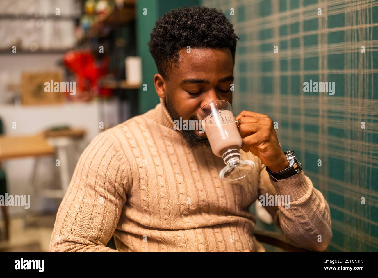Jeune homme noir appréciant le chocolat chaud dans la barre. Portrait de l'homme qui boit du chocolat chaud. Banque D'Images