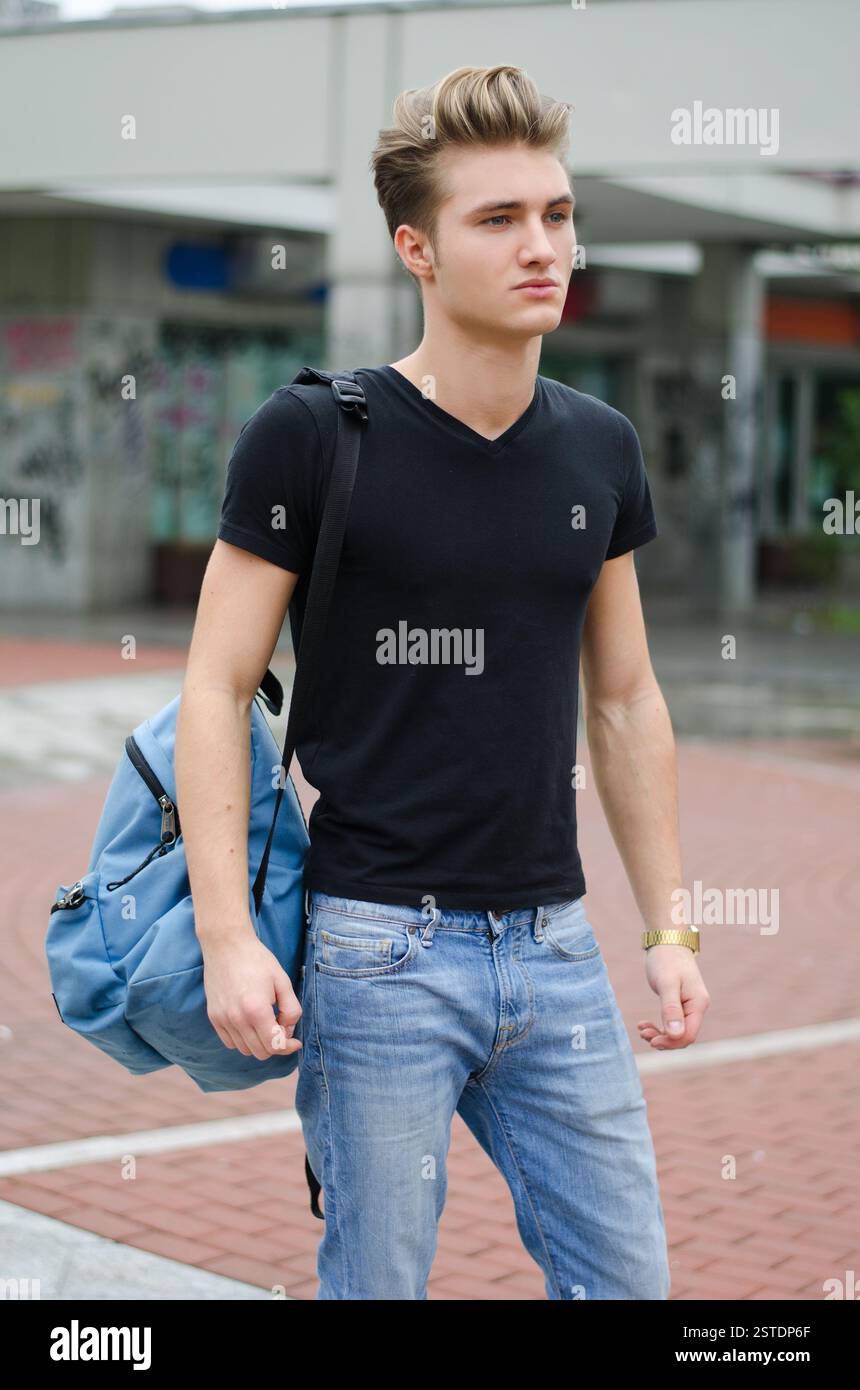Jeune homme attrayant debout dans l'environnement de la ville, avec sac à dos Banque D'Images