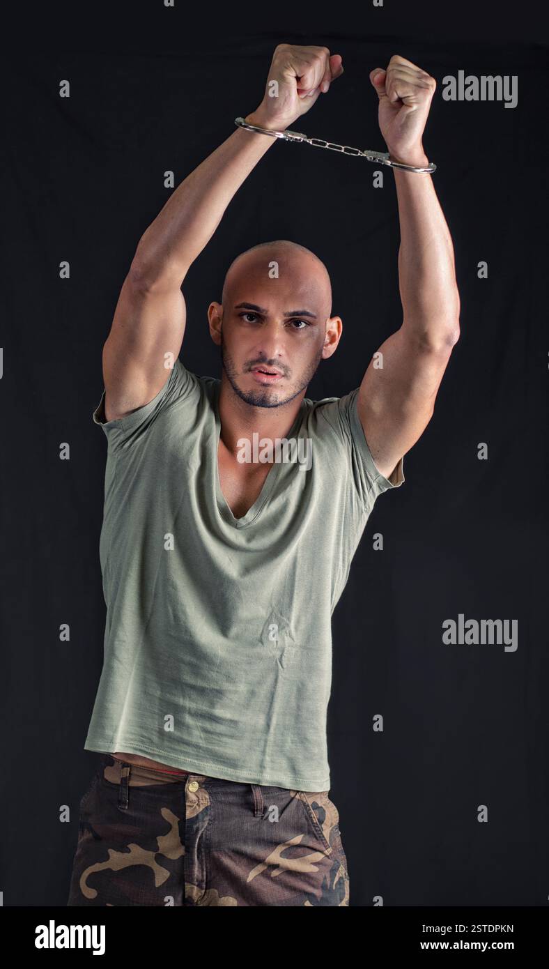 Jeune homme chauve menotté, bras levé Banque D'Images