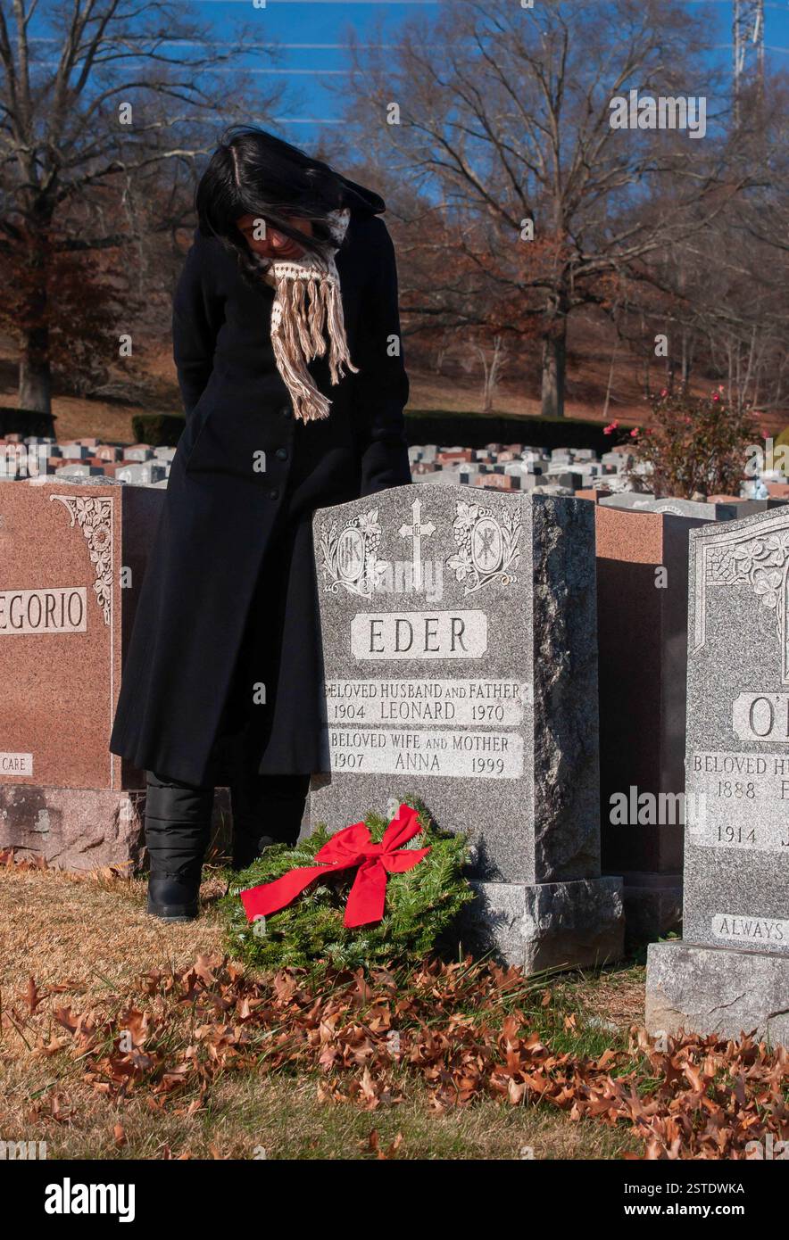 Femmes au cimetière portant un long manteau noir portant une écharpe bleu ciel Banque D'Images