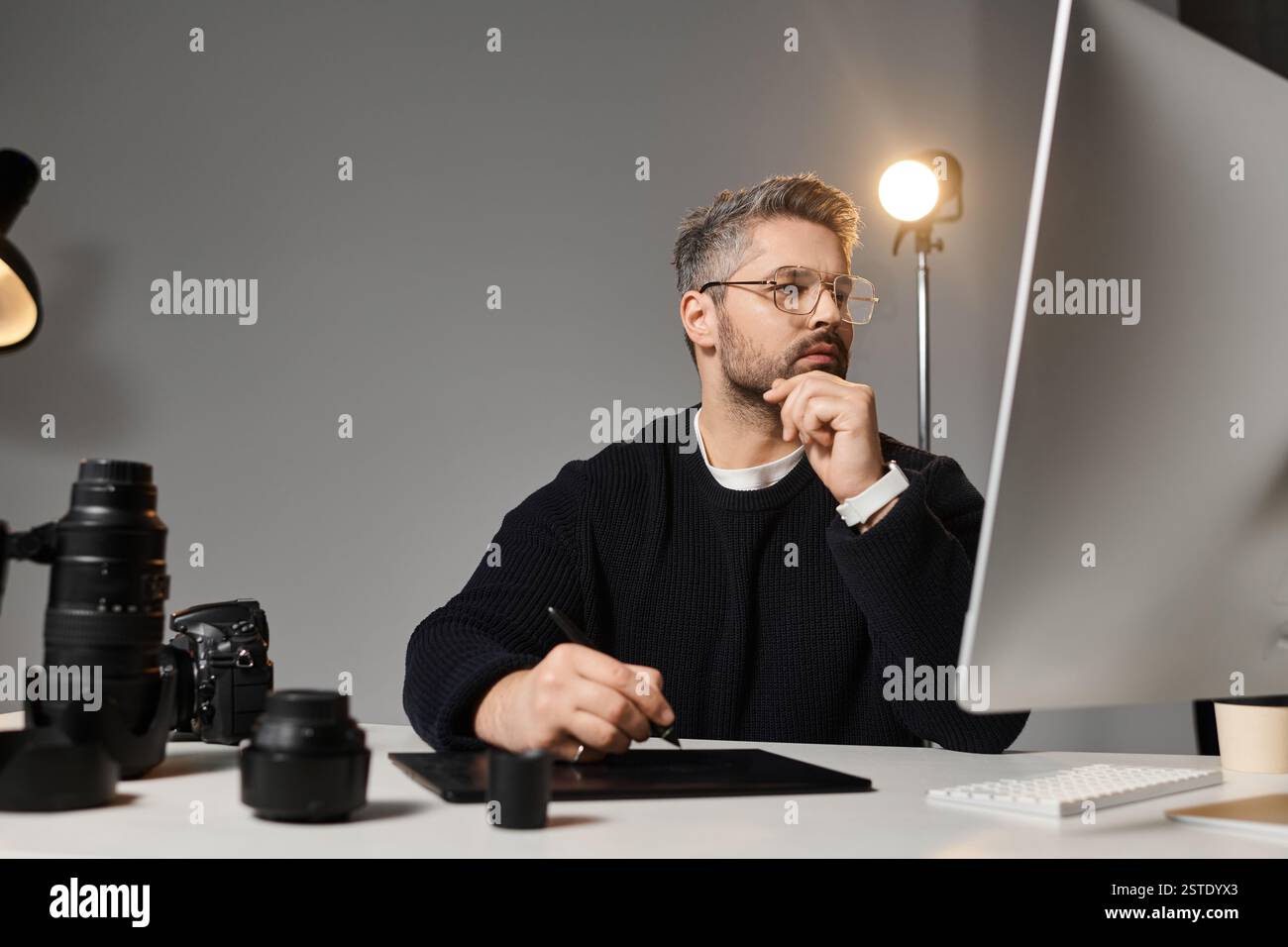 Un homme dévoué édite le contenu créatif à son bureau à l'aide de divers outils. Banque D'Images