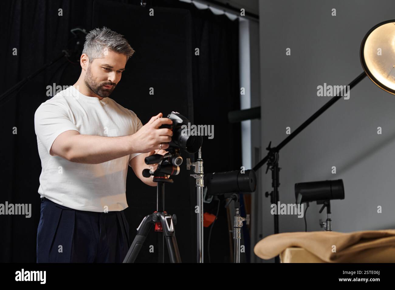Un photographe qualifié ajuste les paramètres dans un studio bien équipé, prêt à prendre des photos. Banque D'Images