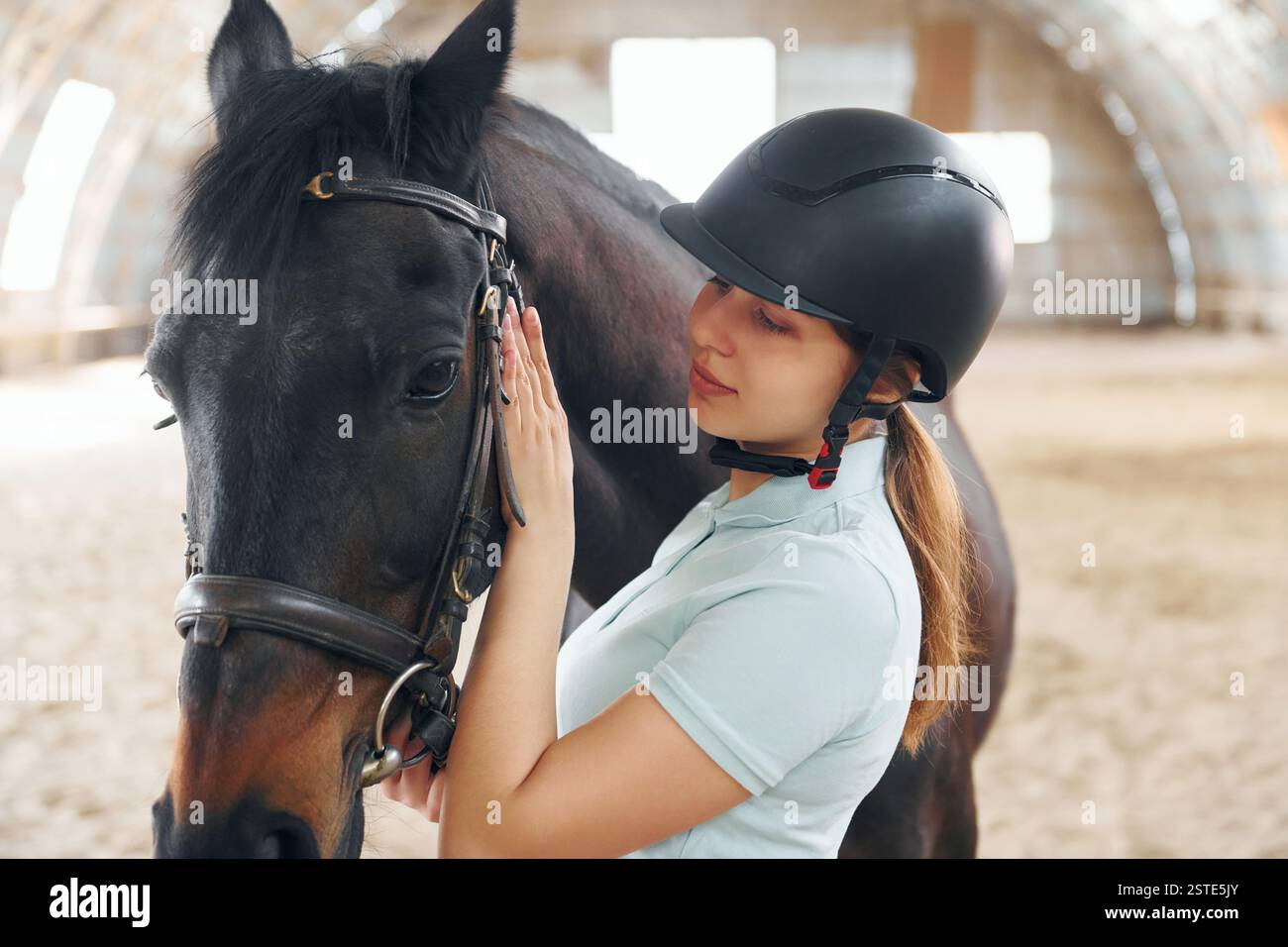 Préparation de l'équipement. Une jeune femme en tenue de jockey est avec un cheval sur une écurie. Banque D'Images
