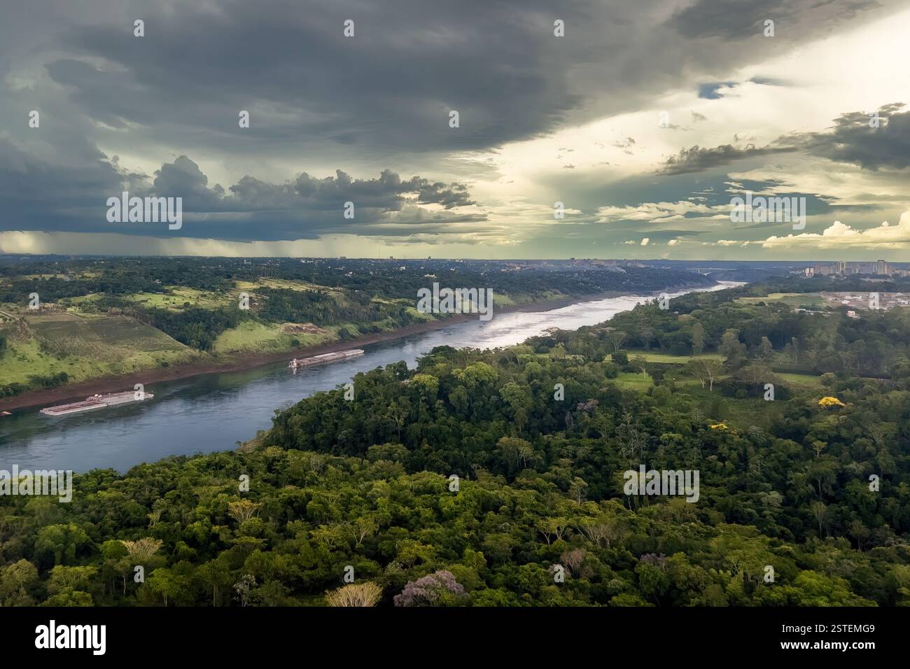 Vue aérienne du paysage verdoyant le long de la rivière Paraná à Foz do Iguaçu, Brésil, avec un bateau naviguant sur la rivière. - Image de stock capturée avec un smartphone