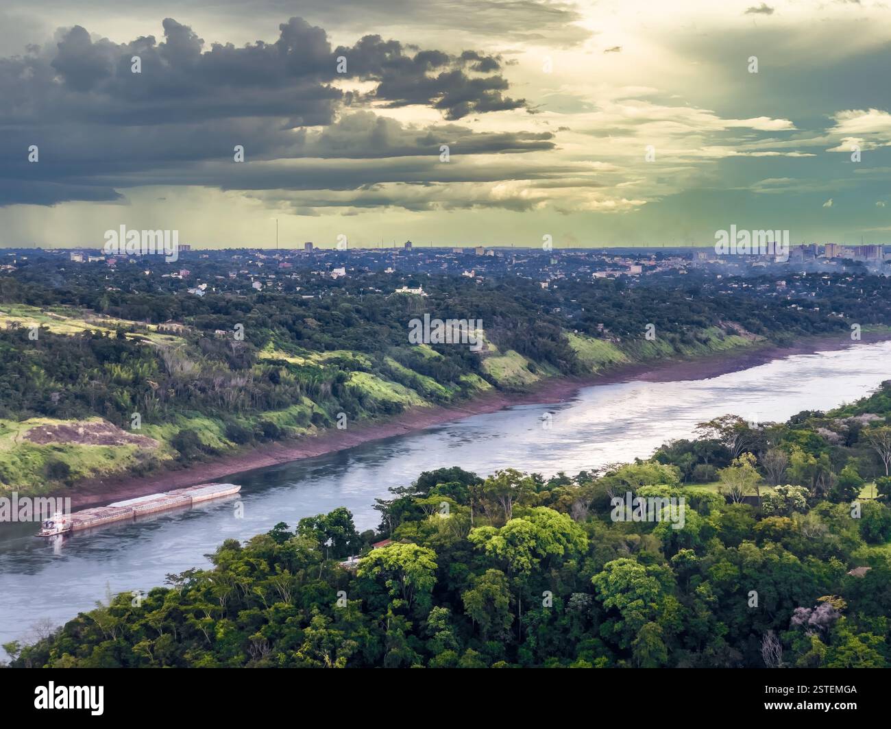 Plan large de la rivière Parana qui coule à travers le paysage verdoyant près de Foz do Iguaçu, avec un cargo naviguant sur la rivière. - Image de stock capturée avec un smartphone