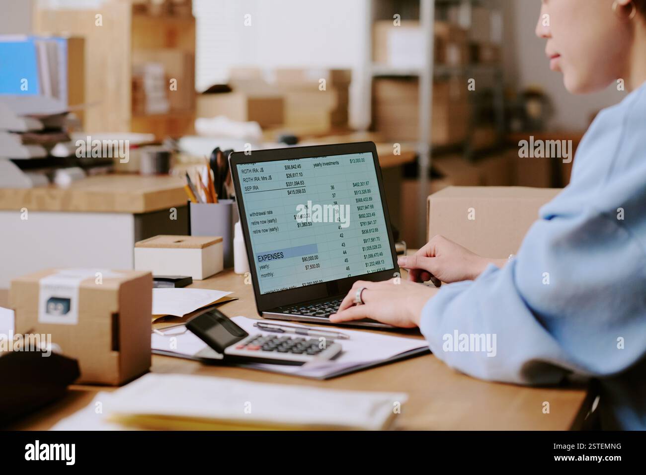 Personne se concentrant sur les documents financiers avec ordinateur portable et calculatrice dans un espace de bureau organisé affichant des données financières et des calculs sans distractions Banque D'Images