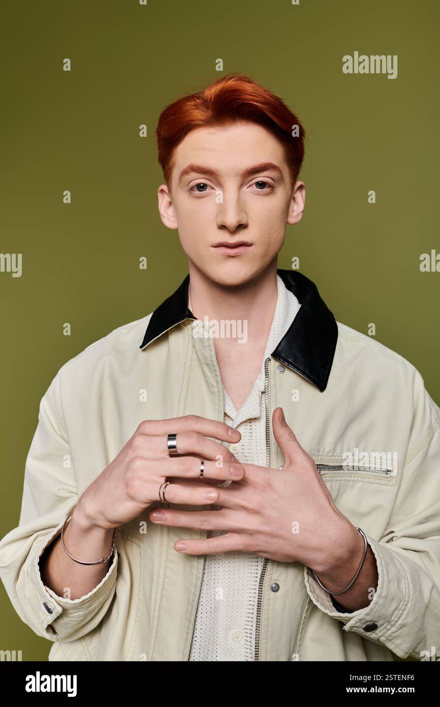 Un homme jeune et beau avec une expression émotionnelle se tient confiant, les mains faisant des gestes significatifs. Banque D'Images