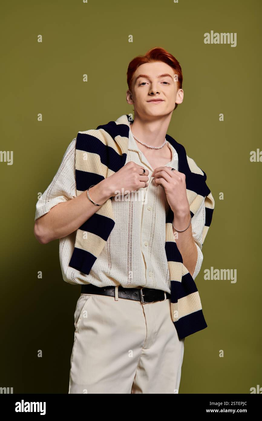 Un jeune homme avec une expression émotionnelle met en valeur son sens de la mode dans un cadre saisissant. Banque D'Images