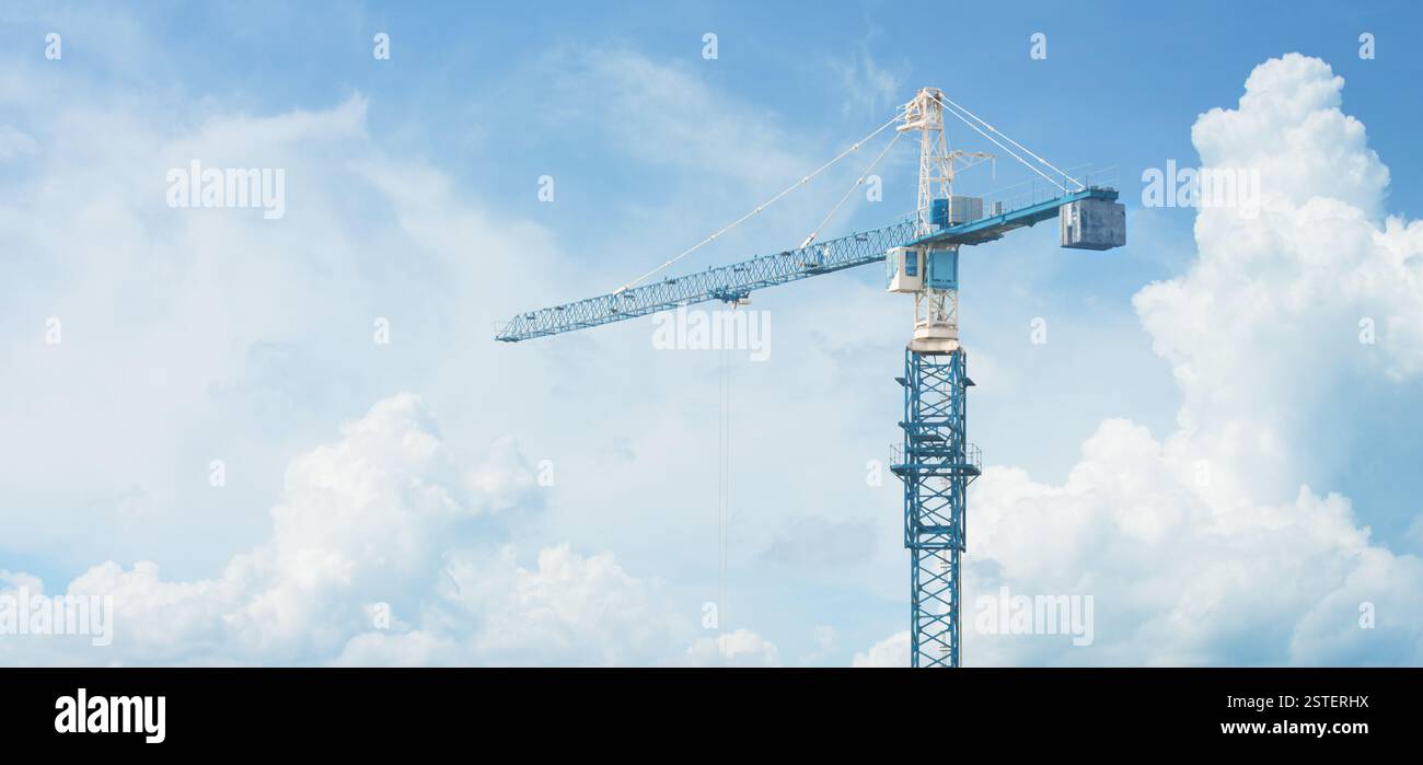 La grue de construction haute se tient contre un ciel nuageux Banque D'Images