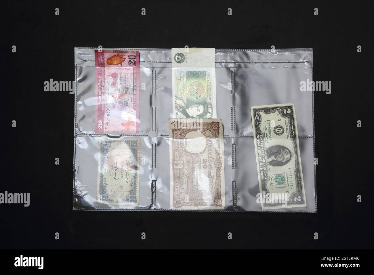 Vieux billets de banque étrangers et en livres sterling dans une feuille suspendue en plastique Banque D'Images