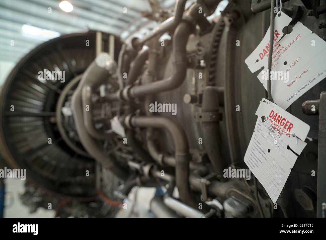 Un moteur d'avion commercial à l'intérieur d'un hangar de maintenance, arborant une étiquette de danger rouge, mettant en évidence la sécurité et l'ingénierie aéronautiques. Banque D'Images