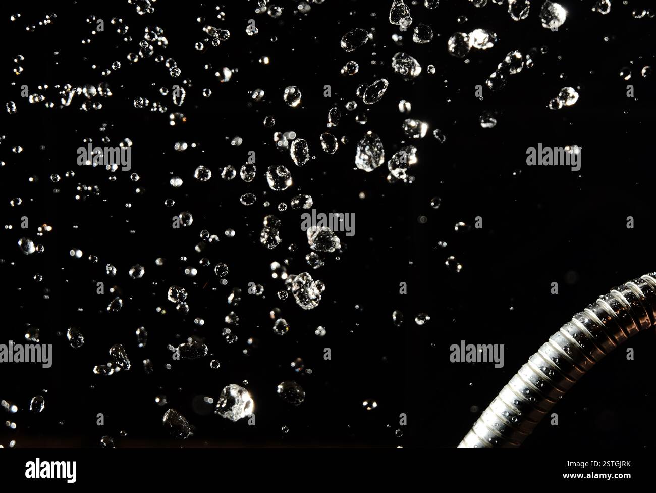 Des gouttes d'eau lévitent sur un fond sombre et un tuyau Banque D'Images