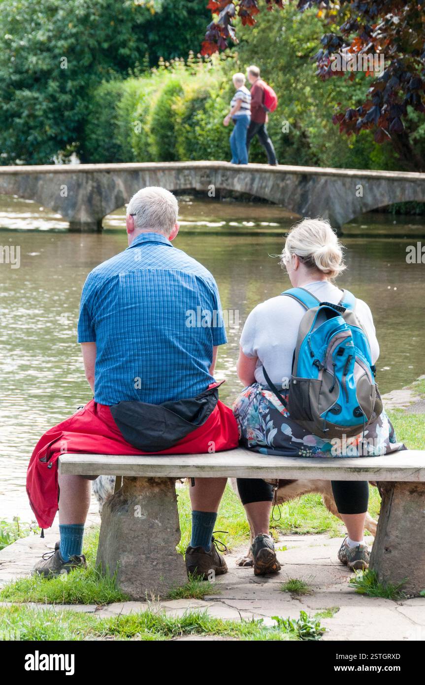Couple de touristes assis à Bourton sur l'eau, Gloucestershire, Royaume-Uni Banque D'Images