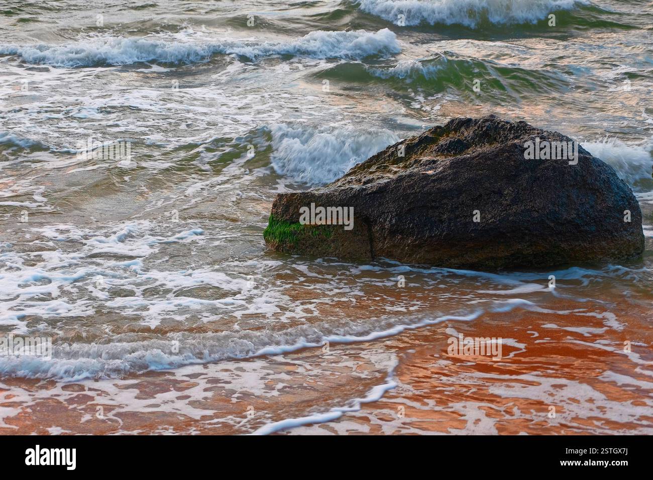 Les petites vagues se brisant sur un rocher Banque D'Images