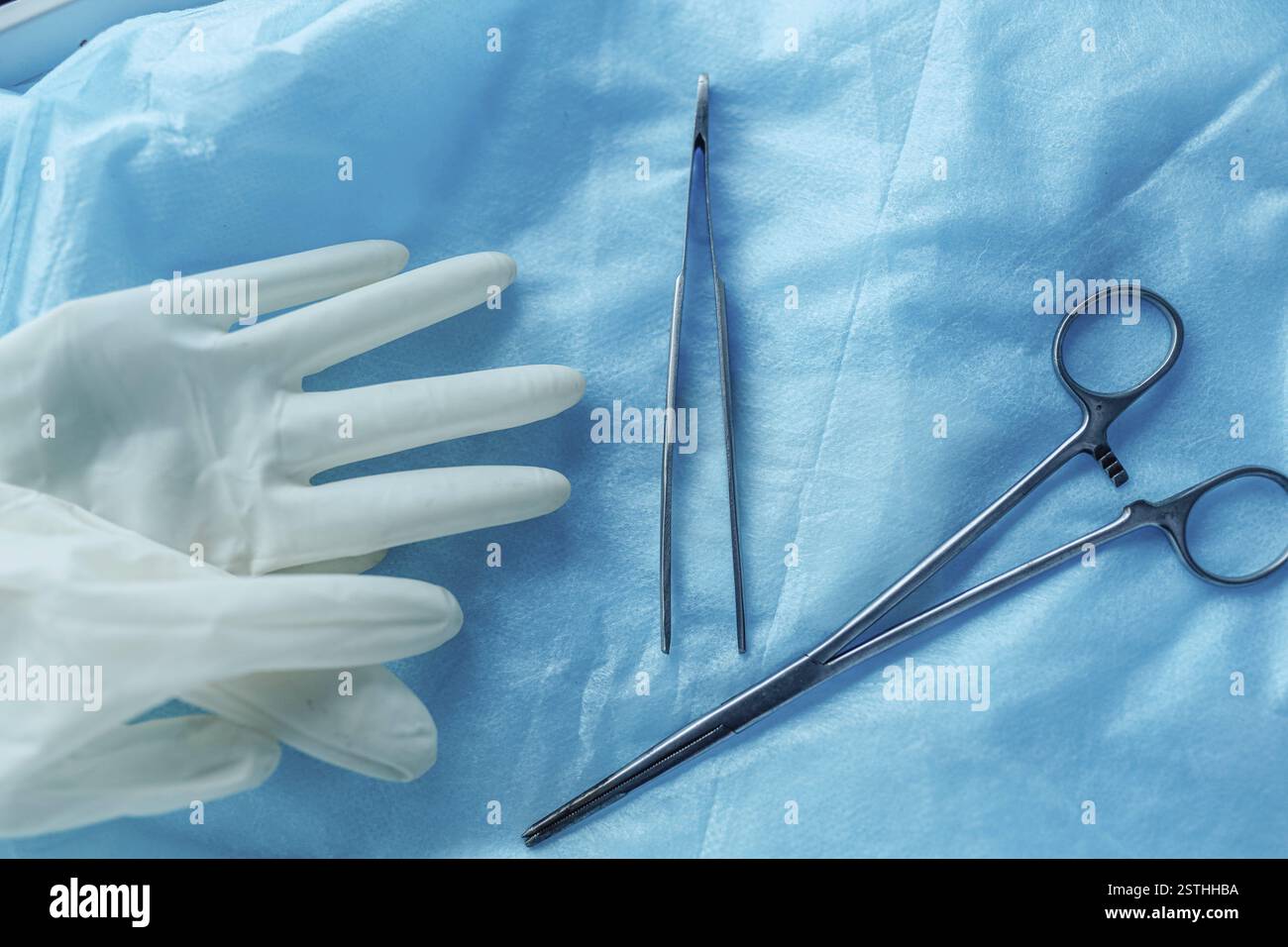 Outils chirurgicaux et gants sur tissu bleu, montrant l'état de préparation pour les procédures médicales Banque D'Images