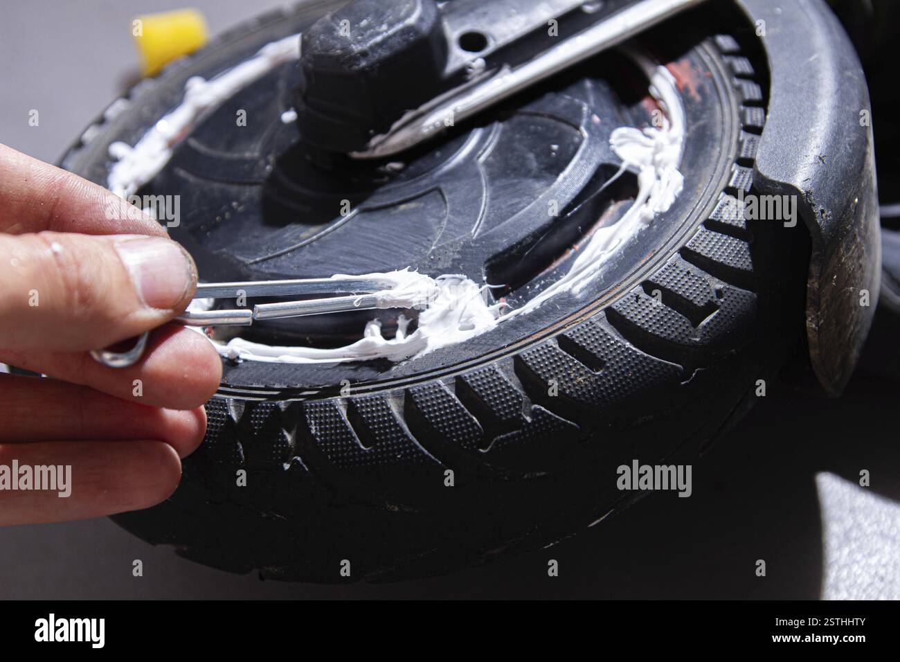 Main appliquant une substance blanche à la roue de scooter à l'intérieur Banque D'Images
