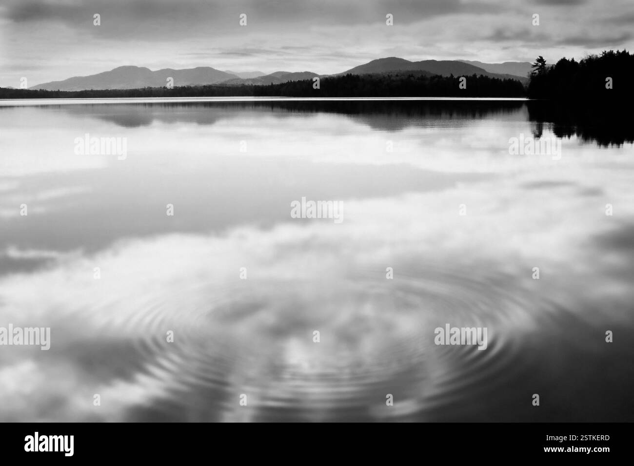 Nuages reflétés dans la surface de l'eau calme, noir et blanc Banque D'Images