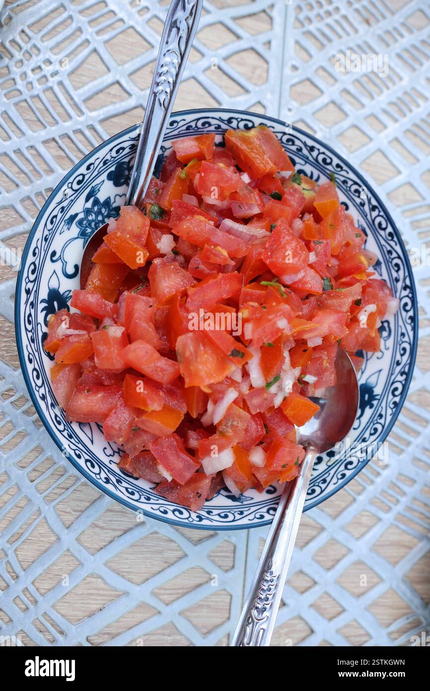 Salade traditionnelle marocaine de tomates servie dans un plat commun avec des cuillères, vue d'en haut. Un plat local simple frais sert couramment. Banque D'Images