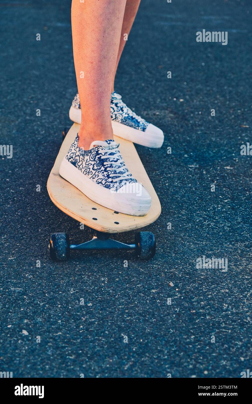Fille debout sur le longboard avec ecchymose sur la jambe inférieure Banque D'Images