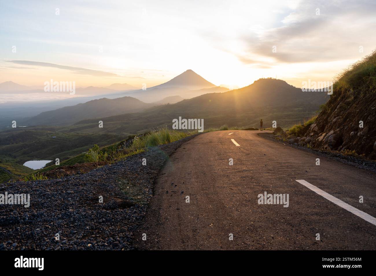 Un lever de soleil à couper le souffle sur une route de montagne sinueuse, entourée de vallées brumeuses et d'un ciel doré. Parfait pour les voyages, l'aventure et les thèmes de la nature. Banque D'Images